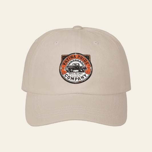 Beige cap with an embroidered Patina Pride patch style logo on the front.